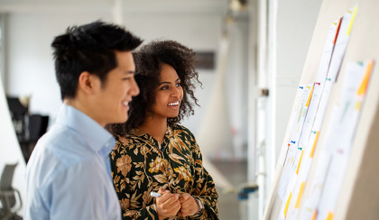 man and women looking at documents pinned to a wall