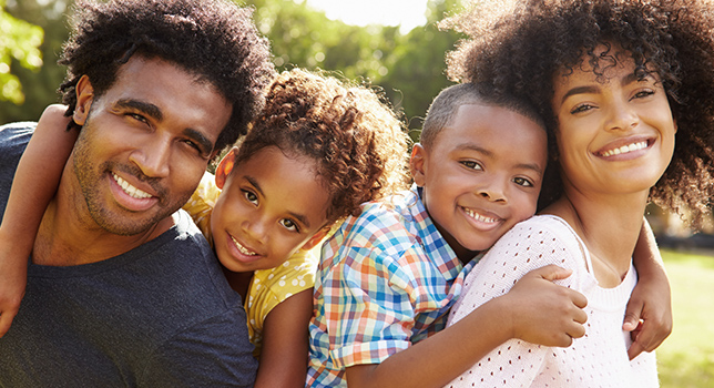 woman and man giving children piggy back rides in grassy field