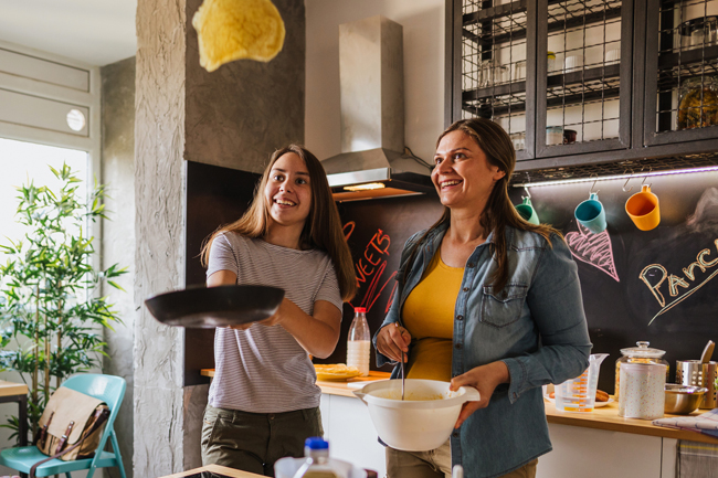 Young mother and daughter with CTF flipping pancakes